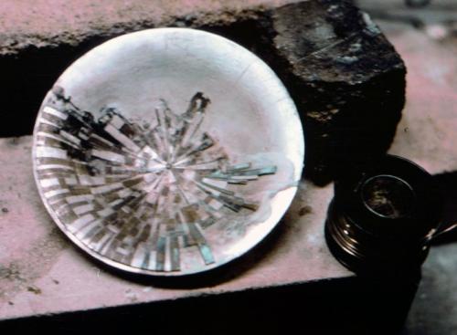Mosaic in the bowl set up for soldering. The ten or so pieces to be attached can be seen at the right. While soldering, care is taken to deflect excess heat away from any previously soldered pattern.