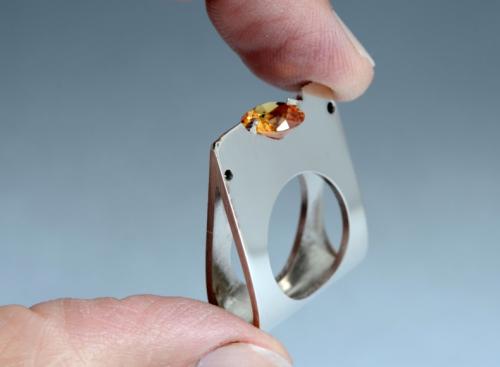 The synthetic corundum is secured by two prongs that were also carved from the solid area of intersection.