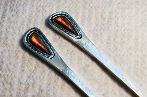 The sterling around the stones is depressed by being carefully and firmly tapped. This forces the metal to displace sideways. Given precise preparation, the metal moves and contacts the stone along the very top of its bevelled edge.