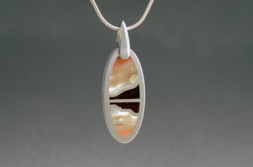 The finished piece with a decorative loop for a chain. The loop is attached by way of a blind rivet through a spacer of tubing inside the hole in the pendant.