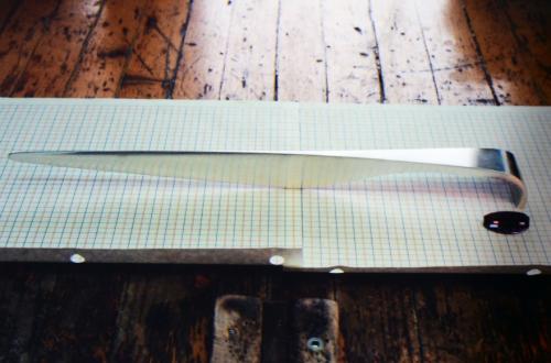 The end of the handle is smithed around to meet perpendicular to the table surface, and the entire piece is planished to a very work-hardened state. The final form and surface is refined and polished.