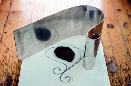 The handle at one end of the sheet is scrolled, and the curve of the pitcher is being bent.