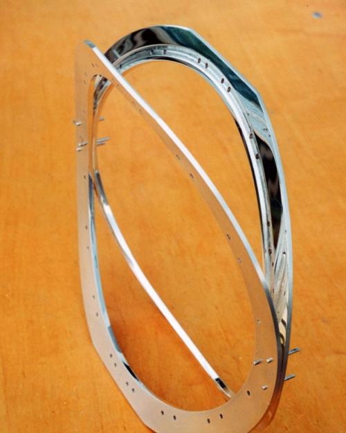 The two framework halves are shown temporarily locked in place with three rivet wires through each area of contact. The recessed tracks for the edge of the labradorite can be seen. The labradorite itself will be drilled and 28 rivet wires will eventually connect through the framework and the stones. 34 holes in the framework are already drilled, 28 of which are in the track.