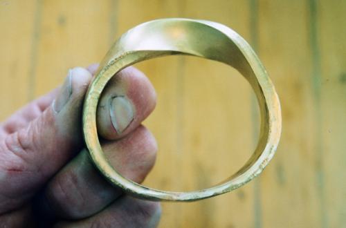 The bracelet is stretched and smithed along a tapered steel mandrel (oval in cross-section) to achieve its final accurate shape. Repeated hammering and annealing is involved.