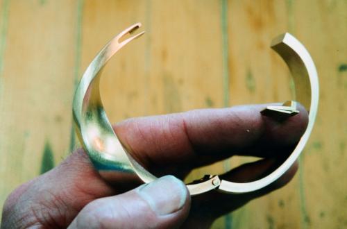 The hinge is shown temporarily assembled while the box catch is being created. The spring for the catch (shown on my finger) will be soldered to the end at the right. Inside the left end, a space is precisely cut out to receive the spring. This stage is the most critical — the "locking" step in the spring must line up perfectly with its corresponding shape in the cut out area.