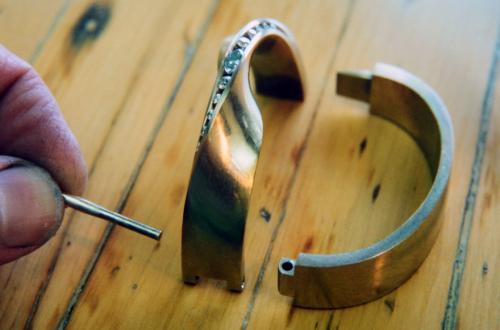 The diamonds are set, and the metal surfaces along the stones are cleaned up. The bracelet is ready for the hinge pin to be riveted in place.