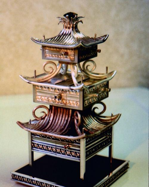 Here the drawers are fully constructed and their handles are set with gems. The bottom two roofs are at different stages of completion. Both now have their edge wires soldered in place which clearly articulate the flipped up corners of the roofs. The lower roof has its pattern of wires partly built in.