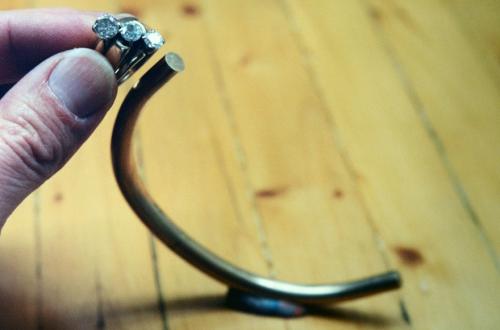 Bending is under way. The thickness of the heavy wire toward both ends is tapered and reduced in diameter to slightly wider than that of the two smaller diamonds.