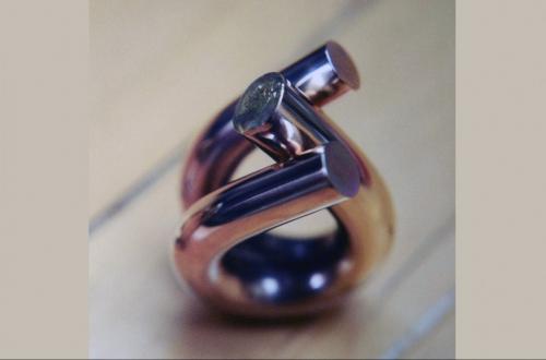 The two facing surfaces have been filed half way through (together their ends become the same circle as the original round heavy wire), and the two halves are soldered together.