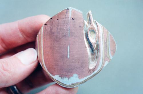 Revealing the pattern. The two areas of pattern near the corners were created by filing through the layers and hammering them smooth. In another area, the layers are carved into and exposed. The process of partially cutting back the top edge of the piece is also beginning and is intended to create the random-edged look of the top of a weathered hollow tree.