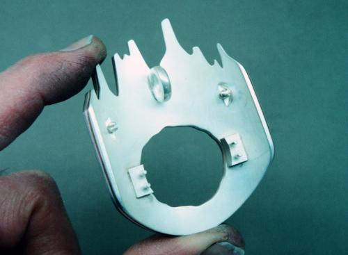The back is prepared with rivets that will eventually secure the assembly that holds the "owl's face." The hinge and catch for the brooch pin are soldered in place, and the loop for chain is also soldered in place.