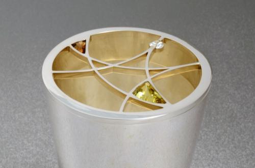 A detail of the finished vase showing the lattice-work insert with three stones — a diamond, a natural tanzanite (brown), and an apatite (green).