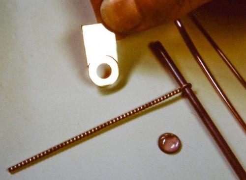 The raw materials — 14 k. red gold (with the table for the stone partly cut out), a rope-like twisted wire, and the cabachon-cut tourmaline.