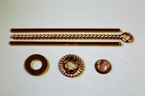 A smaller twisted wire has been made, joined into a circle, and is now soldered around the dome of leaves. Two straight red gold wires are shown with the larger twisted wire — these will be combined to make the ring shank.