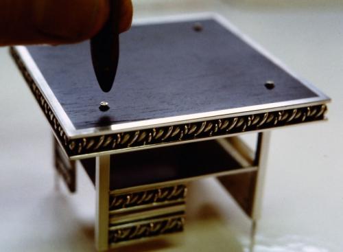 The ebony base is riveted to the bottom layer.