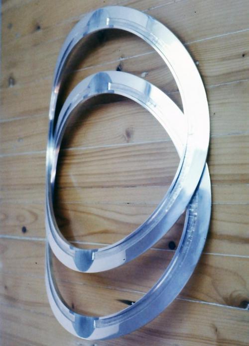 Recessed tracks are precisely carved into the inside surfaces of the shaped circles. These tracks will eventually receive and hold the edges of the labradorite arcs. Matching flat surfaces are also filed where the two framework halves will face together (these appear as shadowy half-circle areas in the photo).