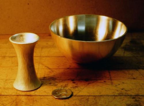 Swaging and flaring the stem. The cylinder is cradled in a steel stake with U-shaped troughs of varying sizes. The size of trough chosen is as close as possible to the diameter of the cylinder. In a process called "swaging," the middle area of the cylinder is hammered with a cross-peen hammer (the oval hammer shape parallel to the length of the cylinder), and as the cylinder becomes reduced in diameter its wall-thickness increases considerably. The two ends are flared by being smithed with a mechanical adva