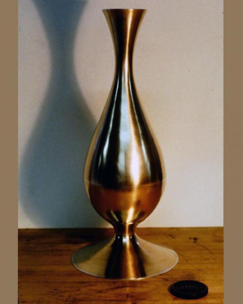 The finished metalwork. The bulb-shaped portion involved more than 50 courses of raising plus considerable swaging of the neck [please see the Chalice process for a description of swaging]. The 12" diameter of the original disc now measures 30". The bulb shape was then cut in half at its widest point, the form refined and planished, and the two halves soldered back together with a strip of sterling silver articulating the join. A sterling edge was also soldered to the rim of the vase. A base was smithed and