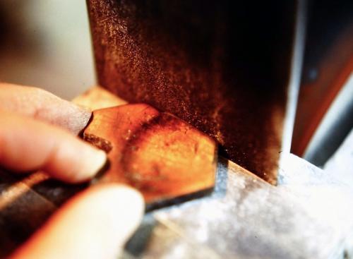 Vertical-sided edges of the labradorite are being shaped on a belt sander.