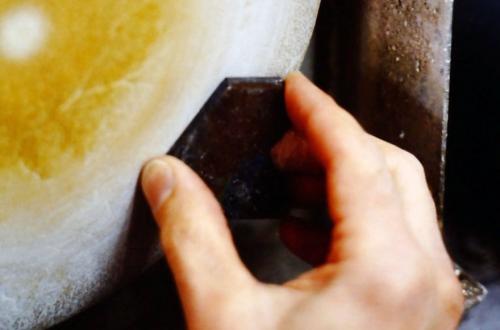 The contoured surface of the labradorite is carved, sanded and hand-smoothed as much as possible, then the surface is given its final polish by being firmly pressed against a spinning chamois wheel (seen here) charged with tin oxide and a bit of moisture.