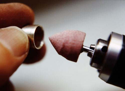 A sterling cylinder has been constructed that is exactly the same diameter as the round citrine. A grinding tool has been custom shaped to exactly the same angle as the underside of the citrine. It is being used to carve a seat in the cylinder to fit the stone.