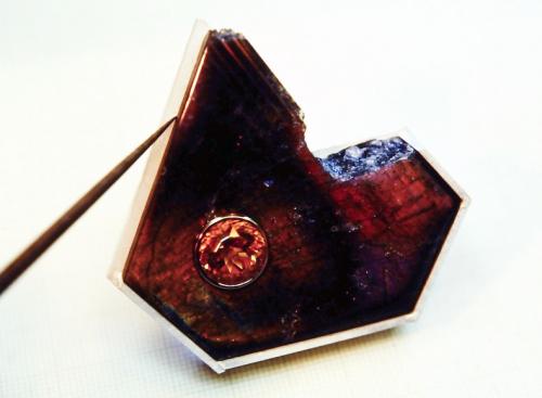 Four out of five sterling walls have been soldered in place on a 3 mm. thick sterling sheet. They are built to precisely fit around the edge of the labradorite. A fifth wall (not yet in place) will go along the upper left side of the stone in the photo. The labradorite is temporarily set in place as a template, and along its edge a distinct line is scratched into the sterling sheet (a sharp tool is shown scribing this line). This marks exactly where the inside edge of the fifth wall needs to be soldered.