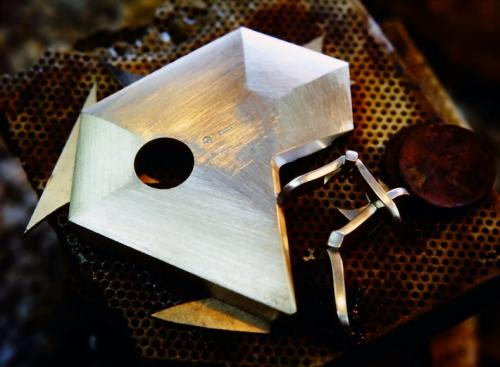 All five walls are soldered in place and the hole in the back for the citrine cylinder is accurately established. Two of the "birds of prey" are joined together and one wing-tip is positioned to be soldered to the pendant.