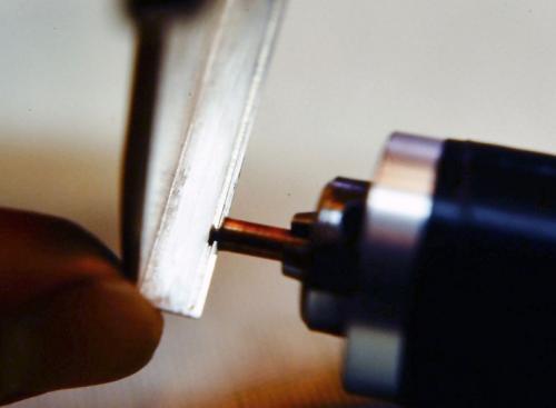 The customized tool is snugly tightened into the Foredom flexible shaft handpiece. The end of the brass tube serves as a guide along the upper edge of the sterling walls. The burr then cuts an absolutely straight groove of consistent depth along the upper inside edge of the walls. The depth should be no more than half the thickness of the wall. The distance down from the wall's upper edge to the groove is barely a millimeter.